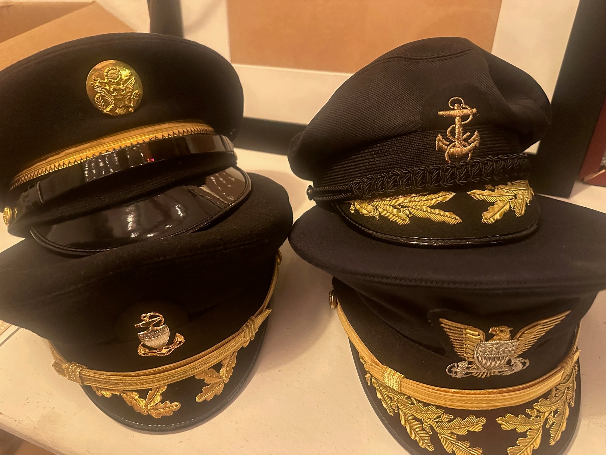 Army and Navy officer visor caps with gold insignia and braid trim