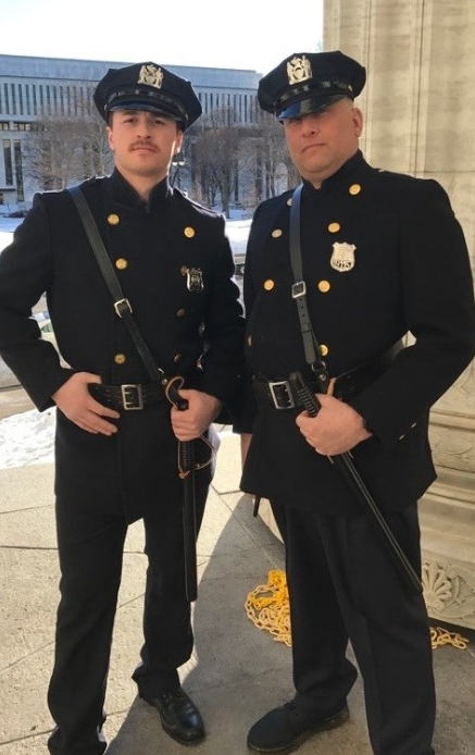 Two NYPD officers in period dress uniforms with caps, badges, and duty belts