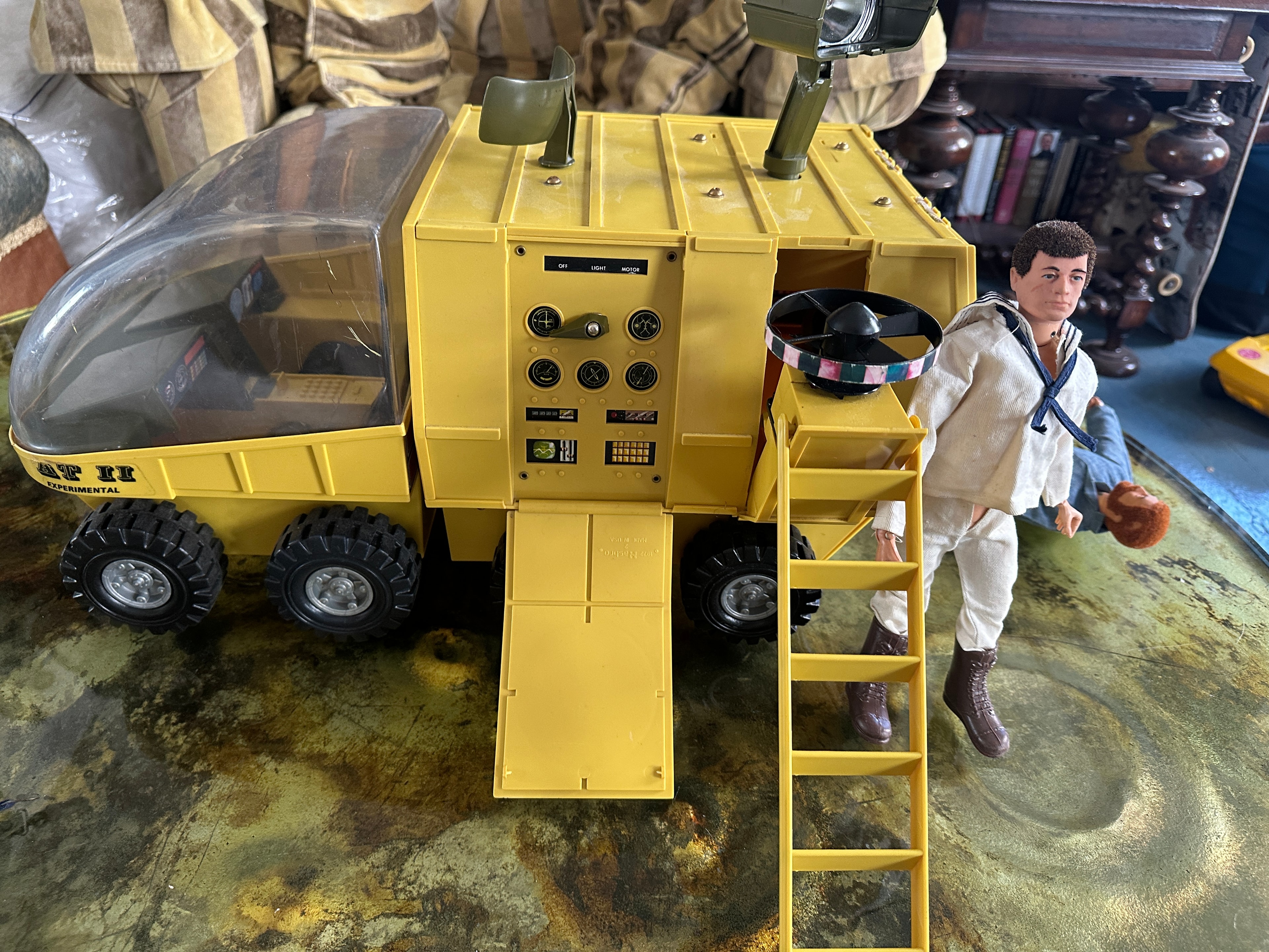 1970s GI Joe AT-2 Experimental yellow vehicle with bubble cockpit, instrument panel, fold-down access ramp, ladder, twin gun mounts, and GI Joe figure in white uniform