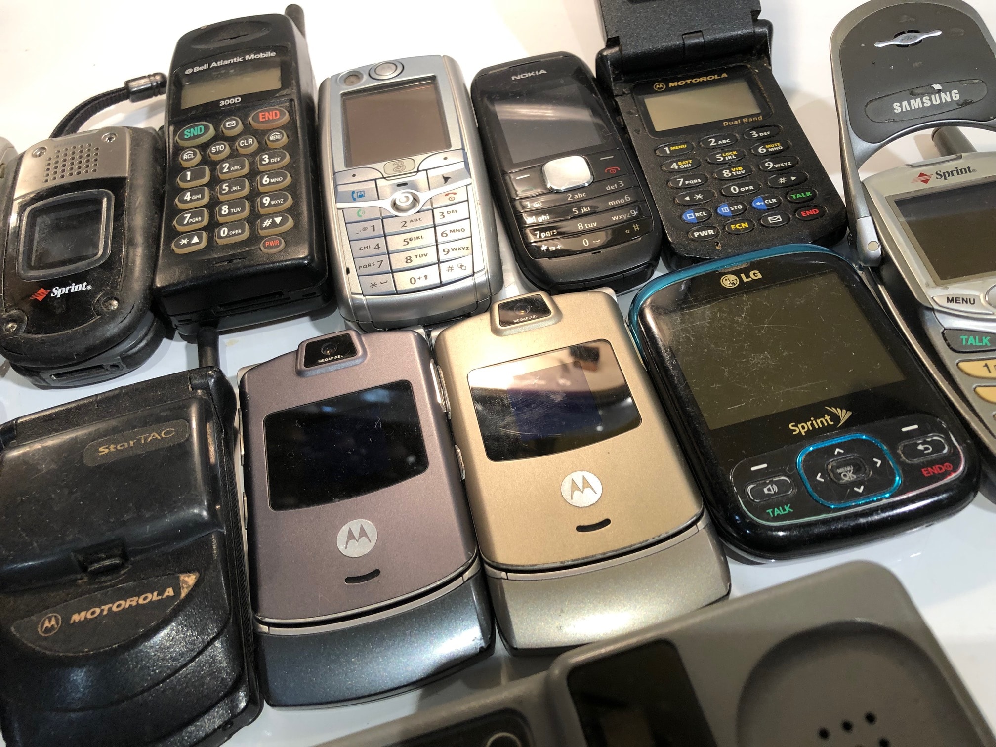 Collection of vintage cell phones including Motorola RAZR, StarTAC, Nokia, LG, Samsung, and Sprint models