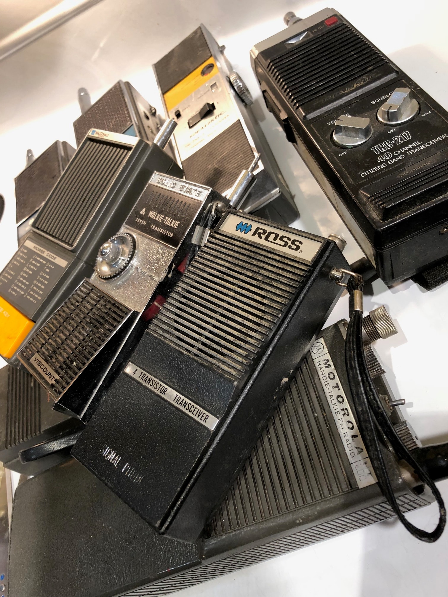 Collection of vintage walkie talkies including Motorola, Ross, and transistor models