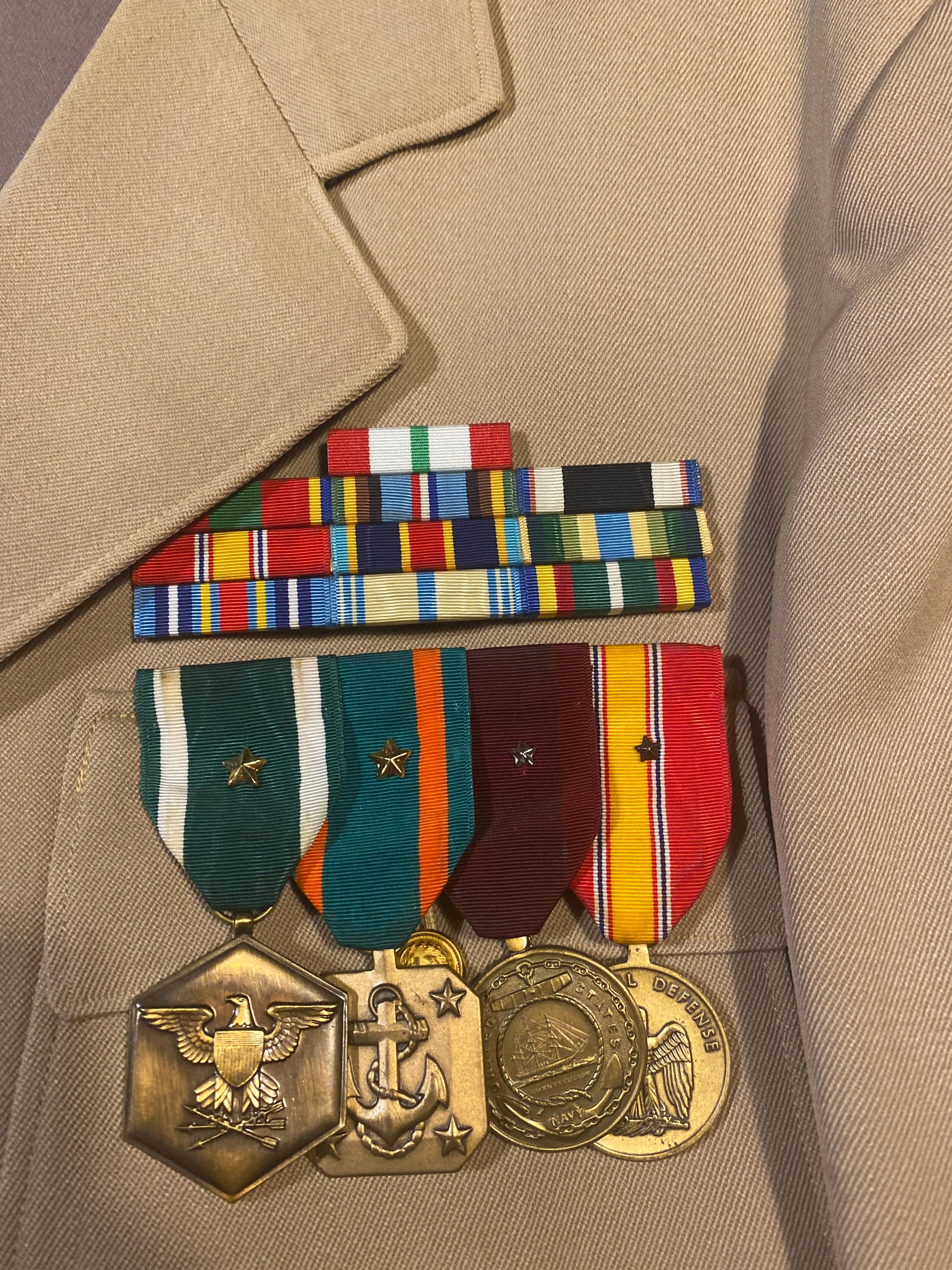 US military medals, ribbon bars, and brass insignia — National Defense Medal, Navy Achievement Medal, anchor device, and eagle badge