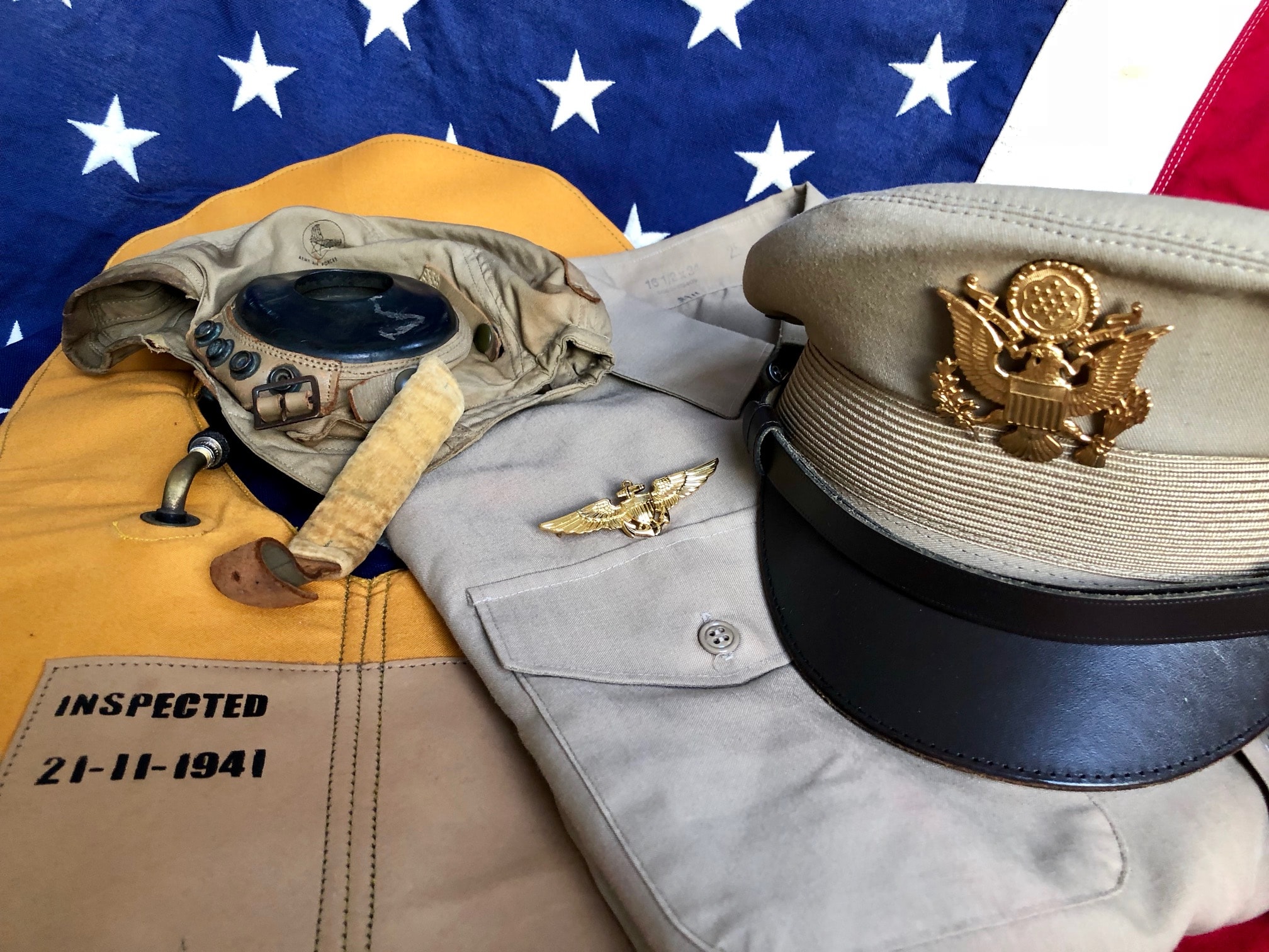 1940s WWII Summer uniform detail — Type B-3 life preserver vest, leather flight helmet, khaki officer shirt with pilot wings badge, and crusher cap with gold eagle insignia